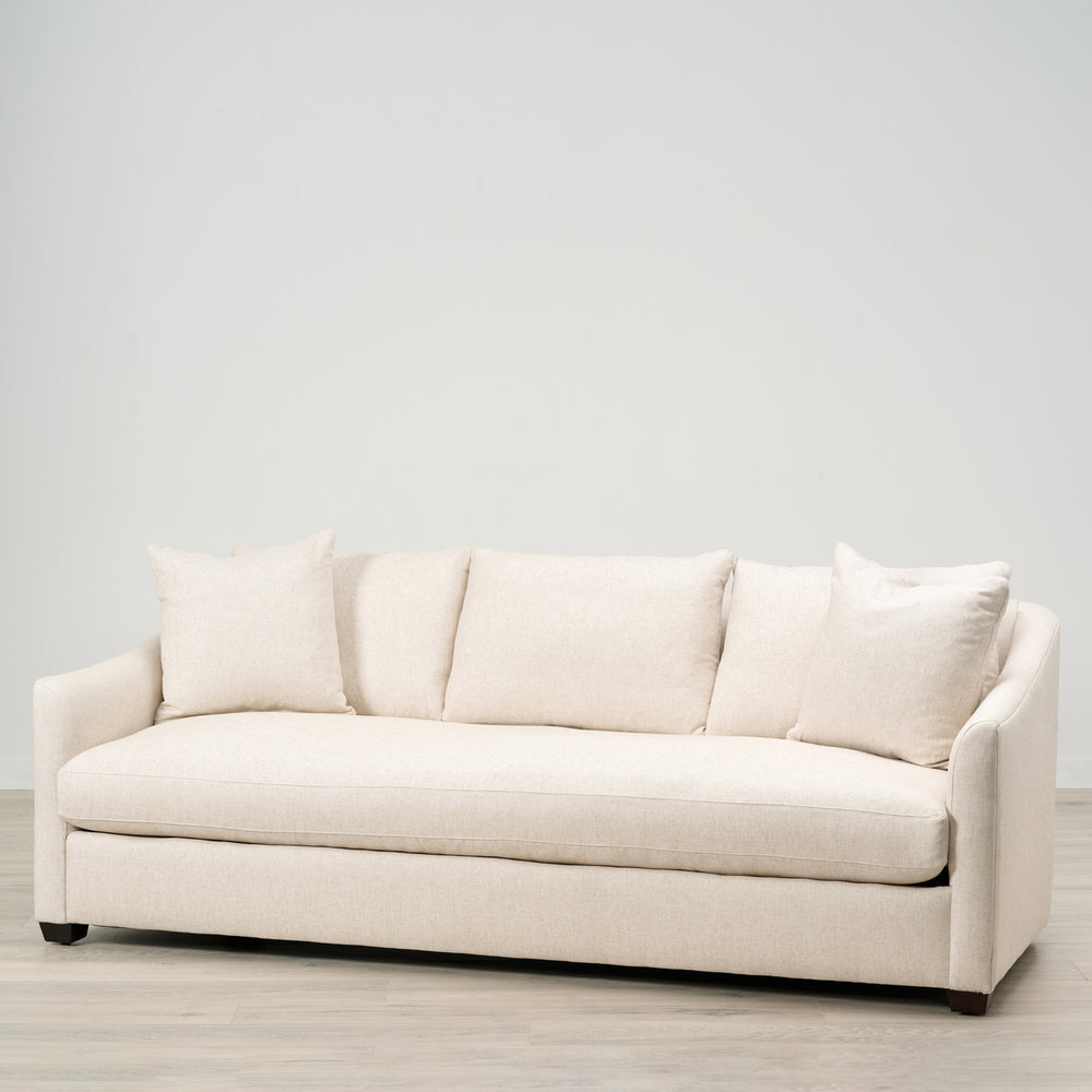 Beige sofa with cushions on a light wooden floor and white wall background