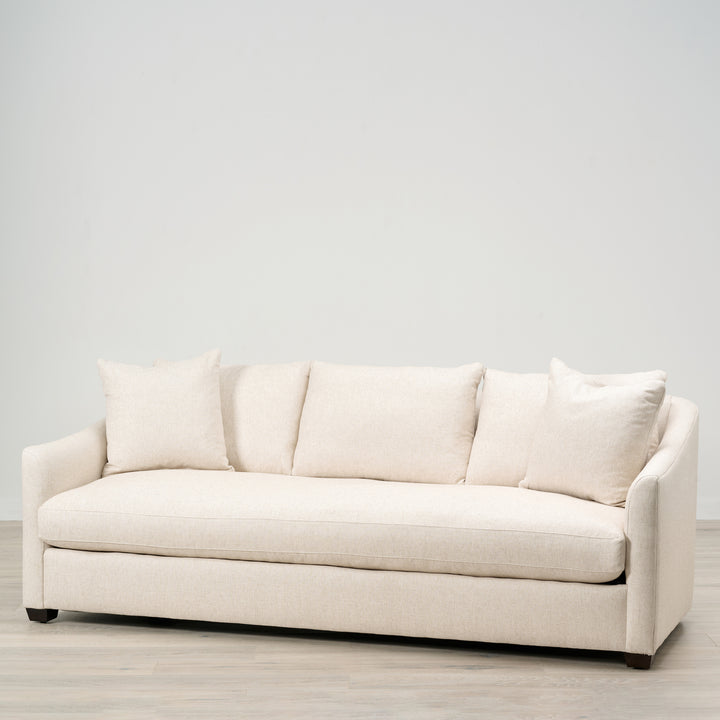 Beige sofa with cushions on a light wooden floor and white wall background