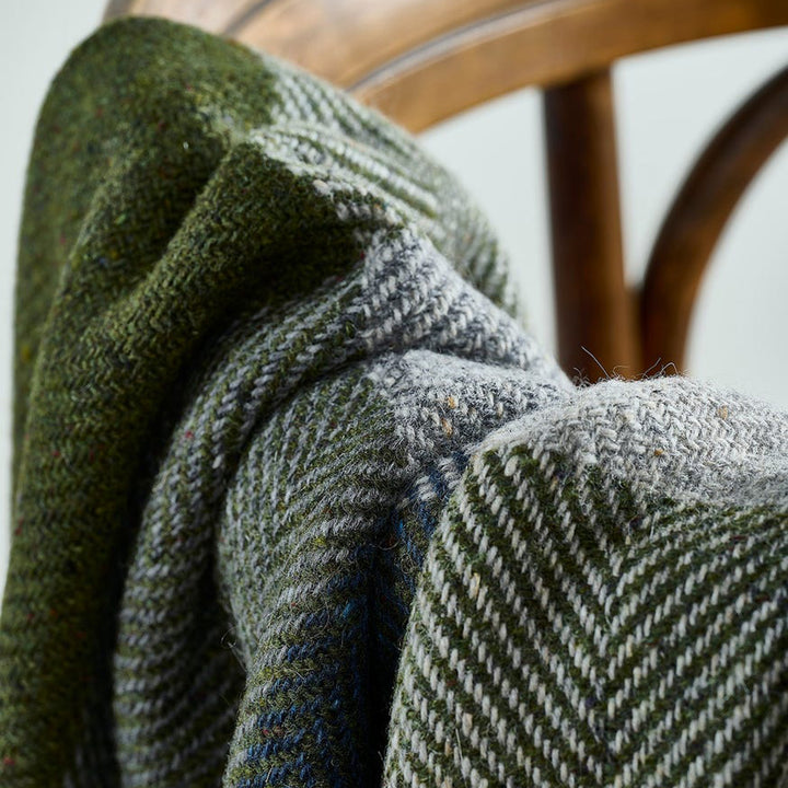 Green and gray herringbone patterned fabric draped over a wooden chair.