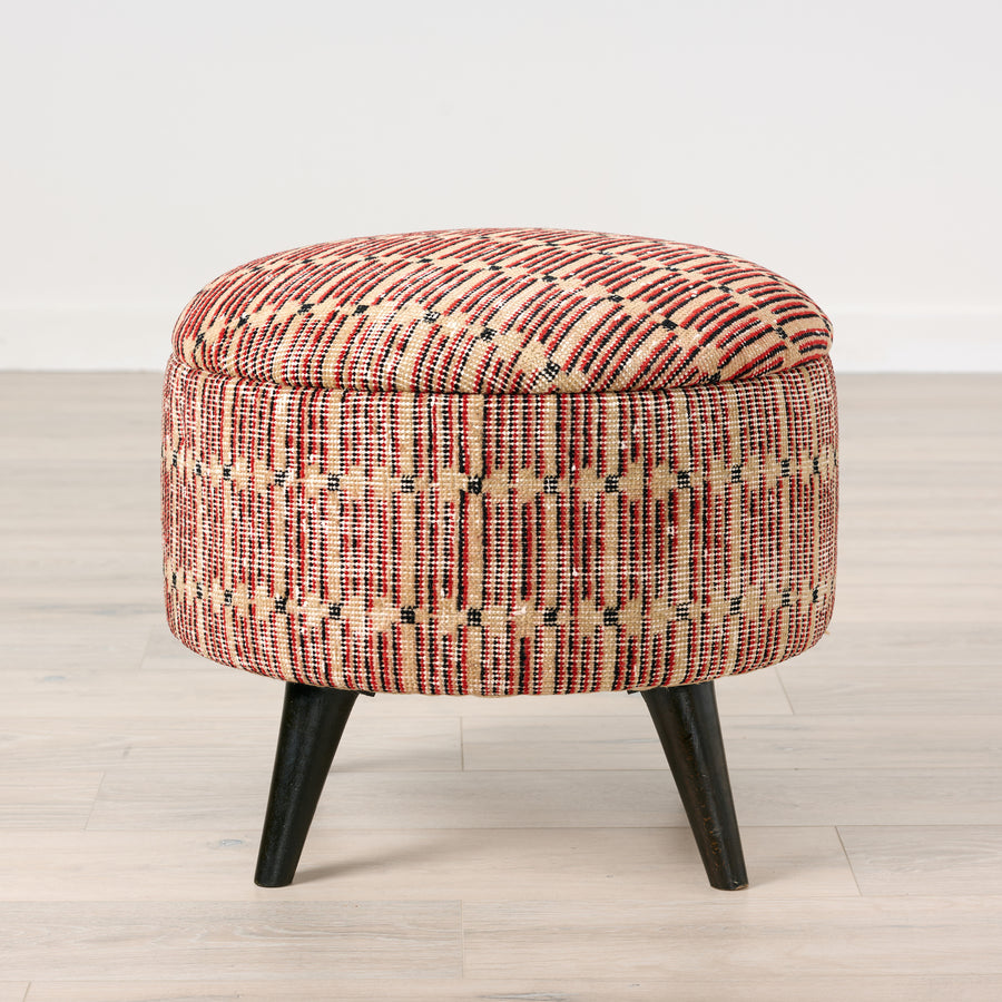 Patterned ottoman with black legs on a light wooden floor.
