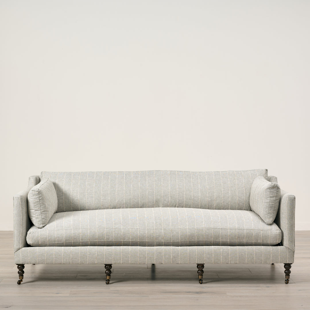 Light gray sofa with a subtle pattern on a wooden floor and light beige wall background