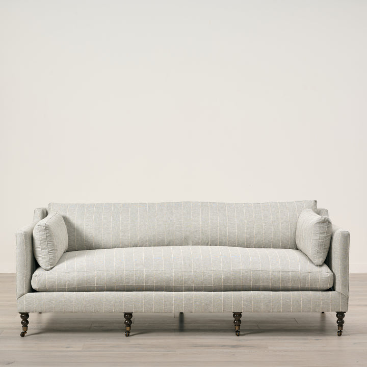 Light gray sofa with a subtle pattern on a wooden floor and light beige wall background