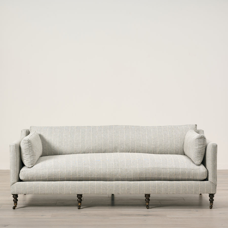 Light gray sofa with a subtle pattern on a wooden floor and light beige wall background