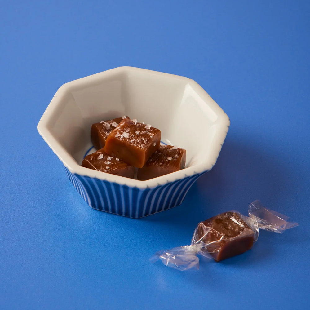 White bowl with caramels on a blue background