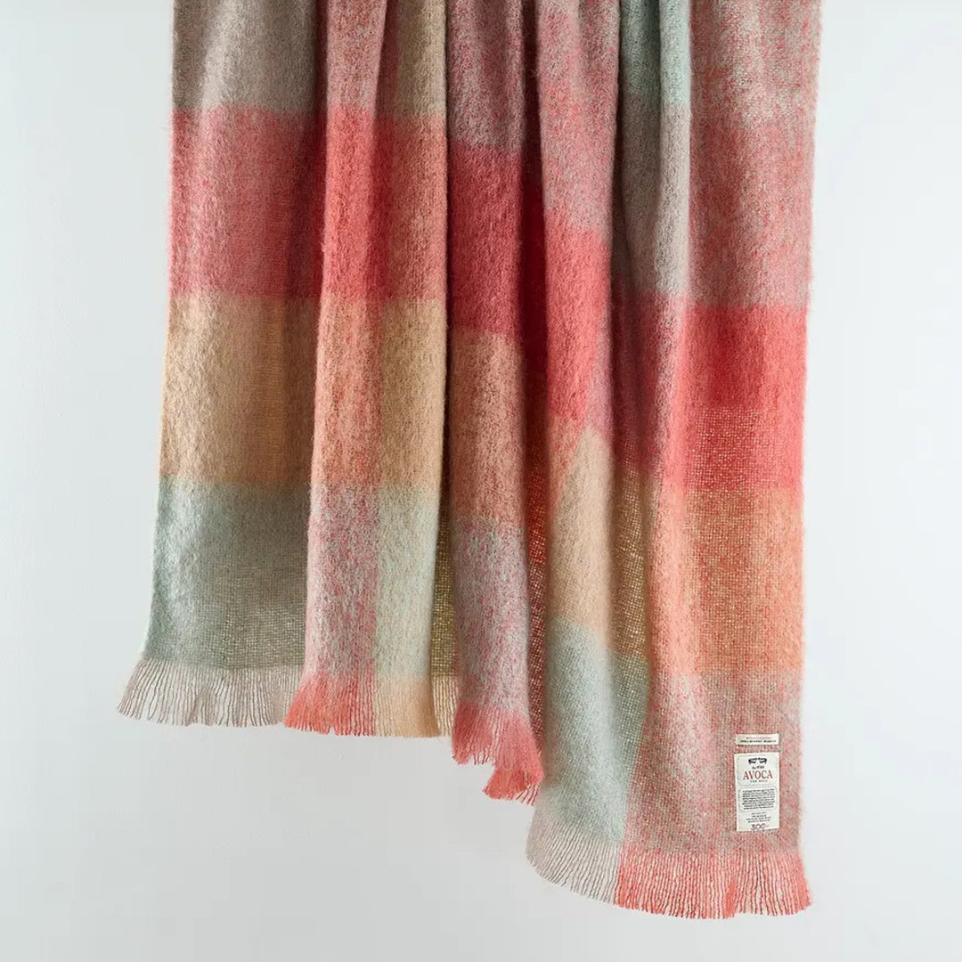 Plaid blanket with red, brown, and beige colors on a white background