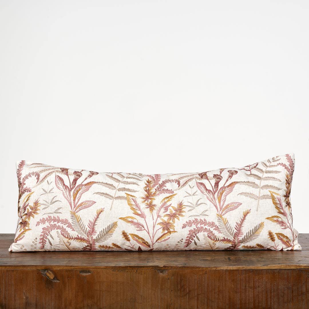 Decorative pillow with leaf pattern on a wooden surface against a white background