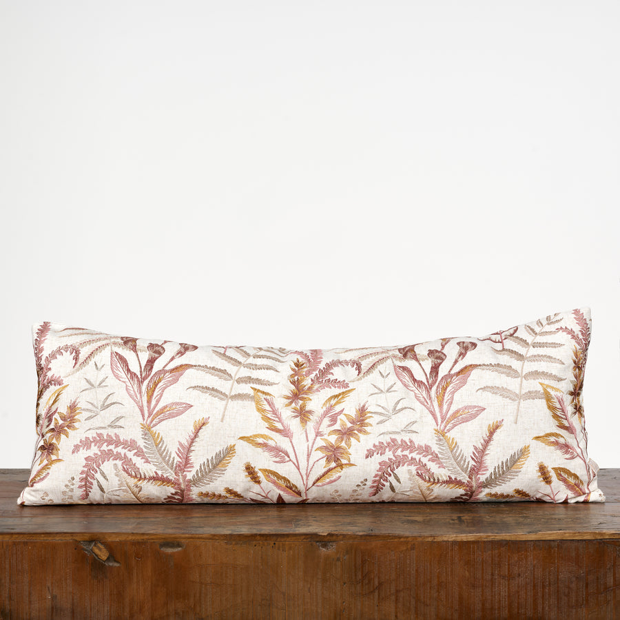 Decorative pillow with leaf pattern on a wooden surface against a white background