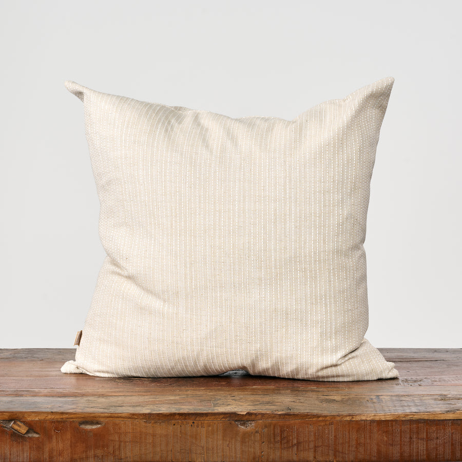 Beige pillow on a wooden surface with a light gray background