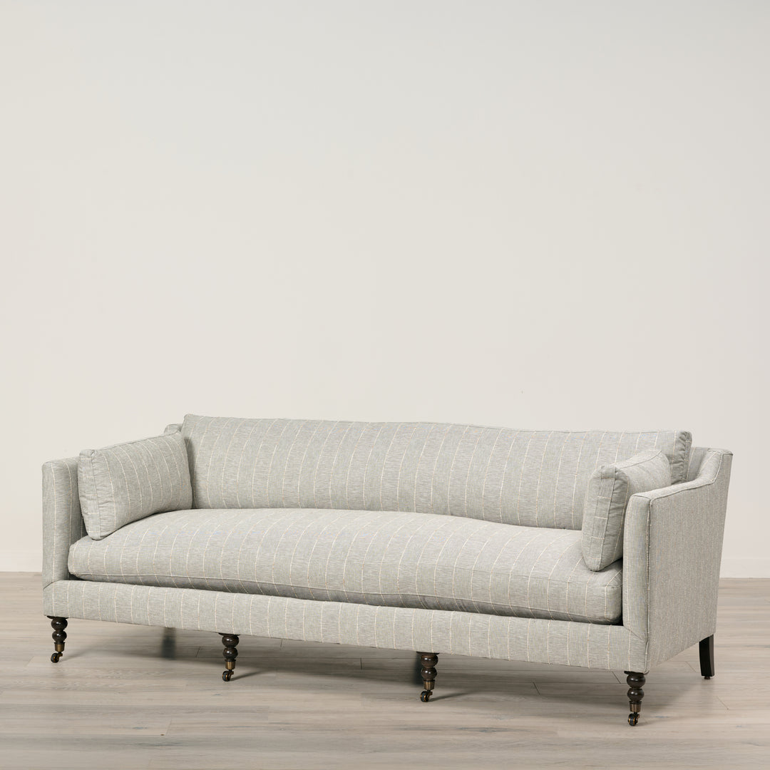 Light gray sofa with a subtle pattern on a wooden floor and light gray wall background