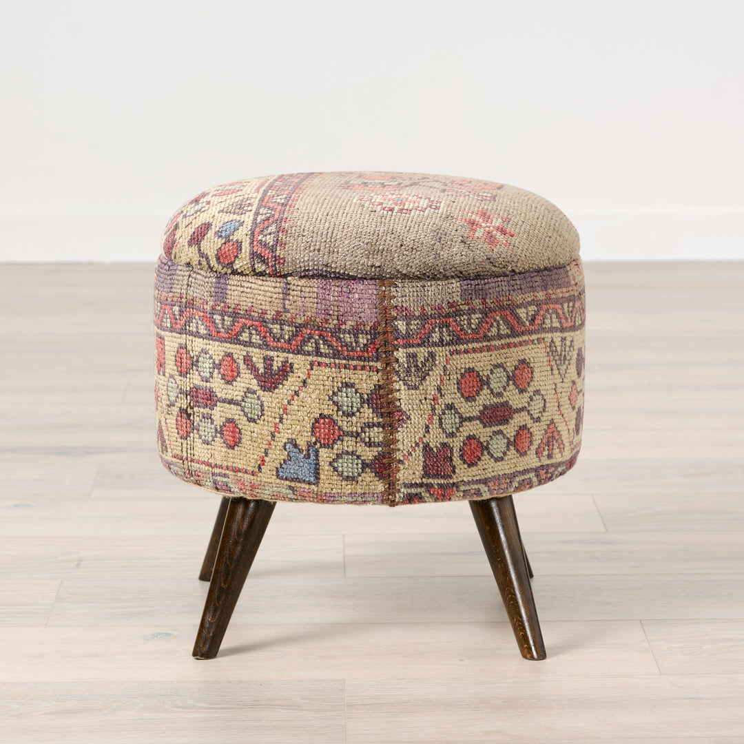 Round ottoman with patterned fabric cover on a wooden floor.Vintage Rug Small Ottoman 0725-A.