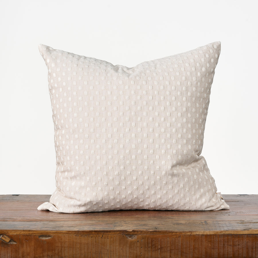 Beige pillow with subtle pattern on a wooden surface