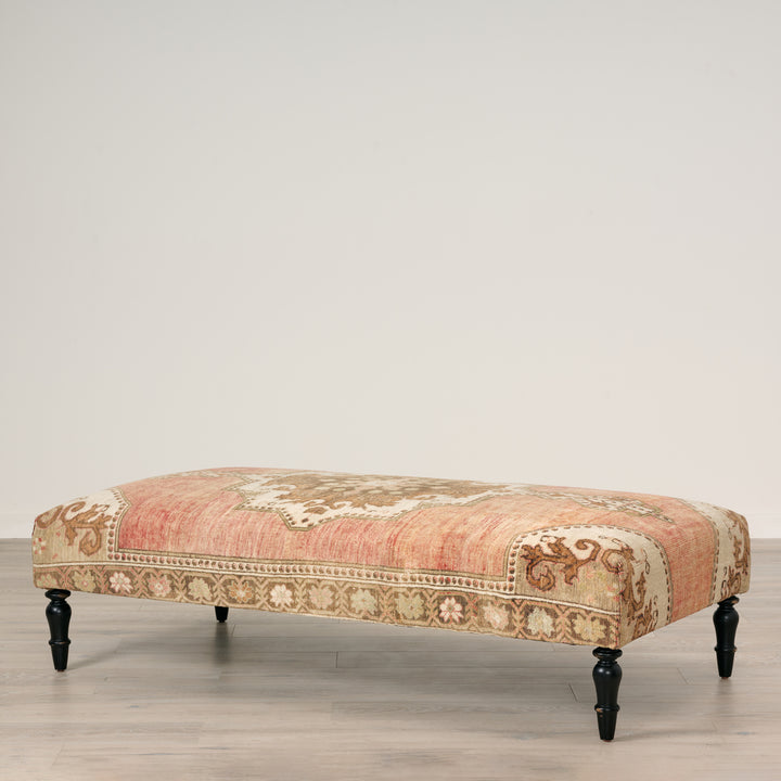 Decorative bench with floral pattern on a wooden floor against a plain wall
