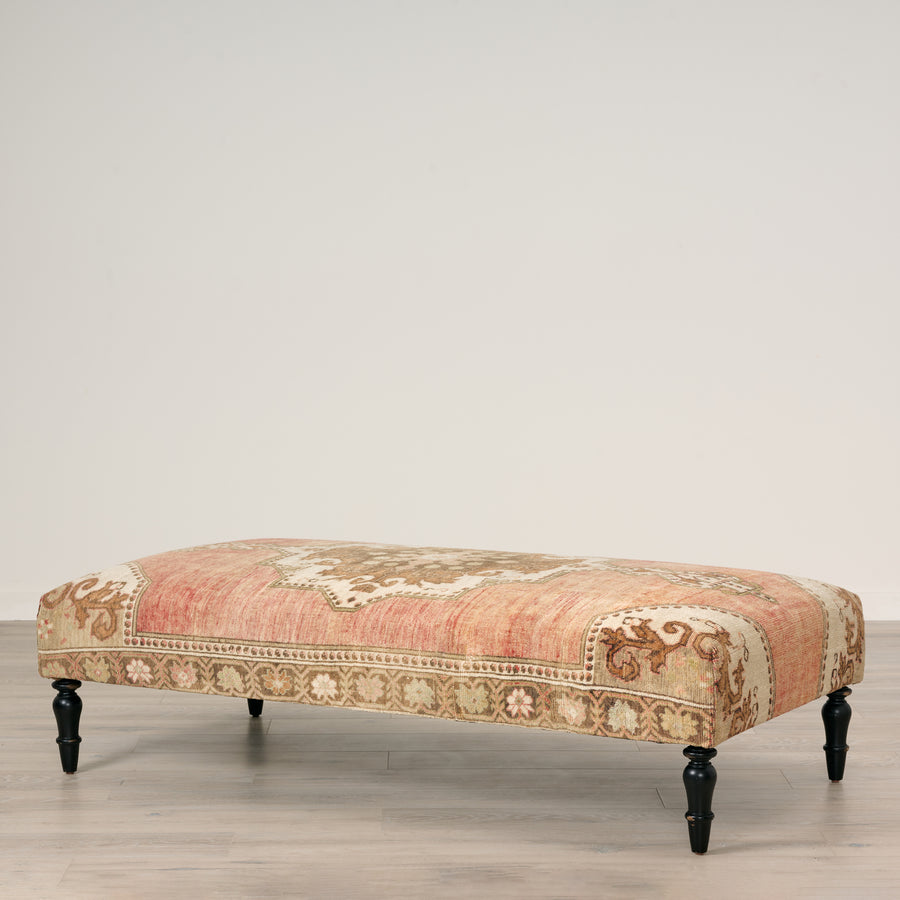 Decorative bench with floral pattern on a wooden floor against a plain wall