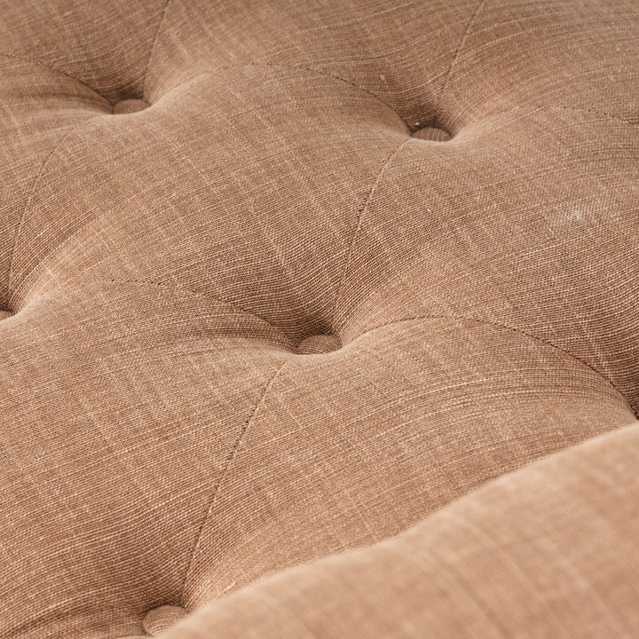 Close-up of a brown textured fabric surface with tufted design