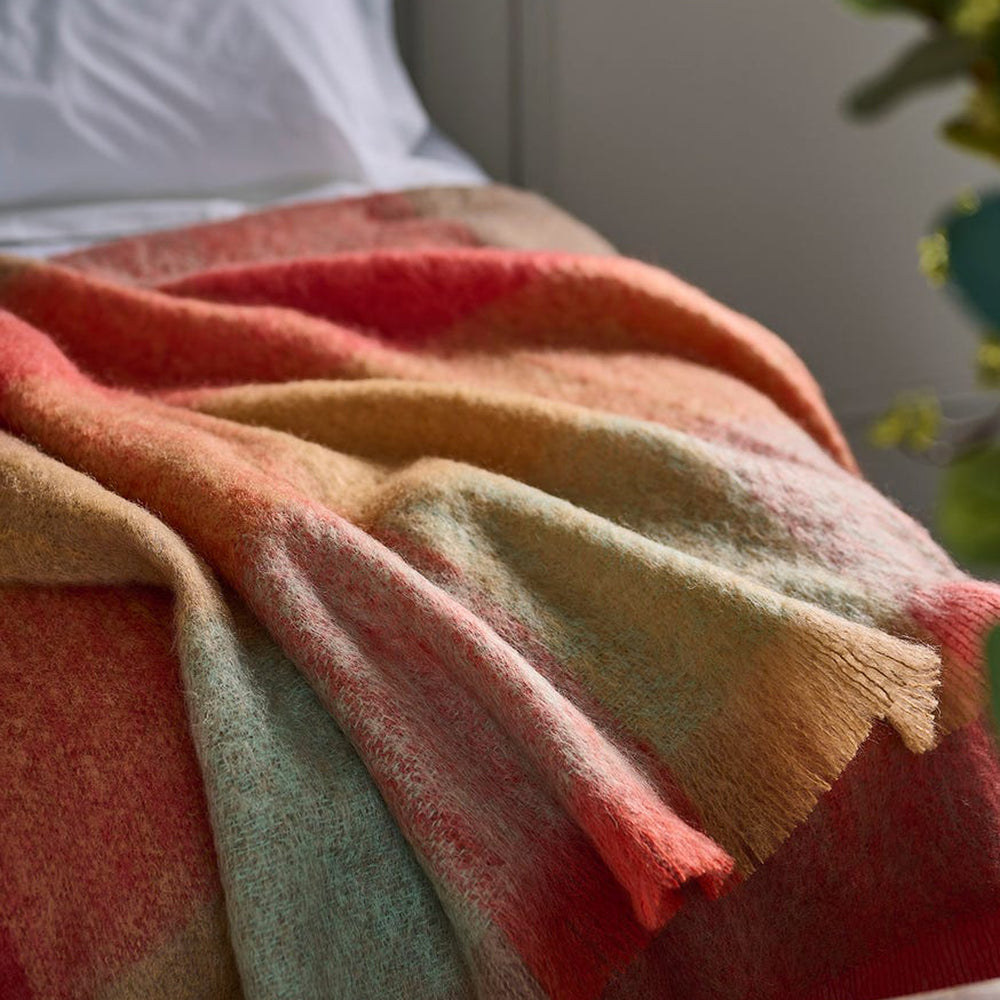 Multicolored blanket with red, orange, and green hues draped over a surface.