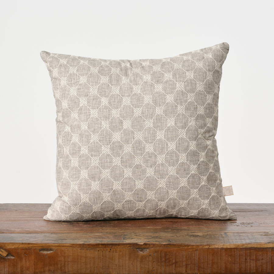 Patterned pillow on a wooden surface with a white background