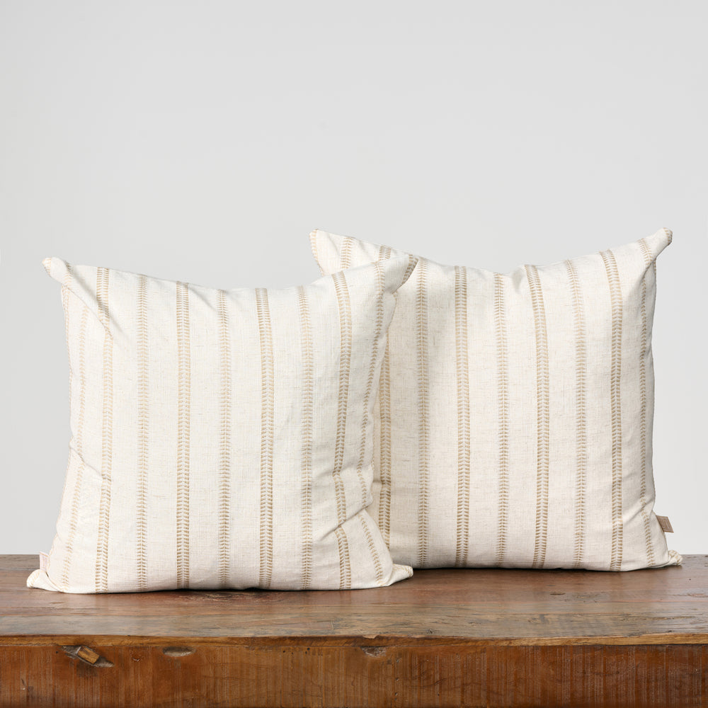 Two striped pillows on a wooden surface with a light gray background