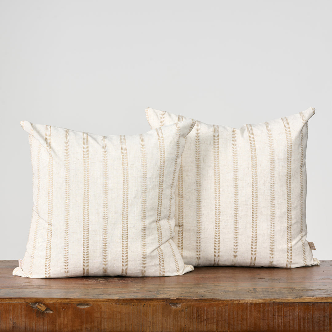 Two striped pillows on a wooden surface with a light gray background