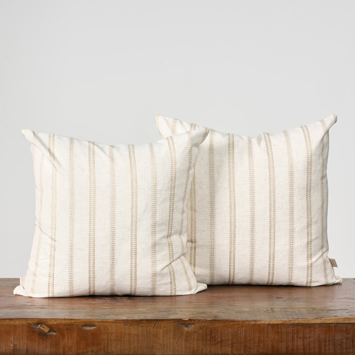 Two striped pillows on a wooden surface with a light gray background