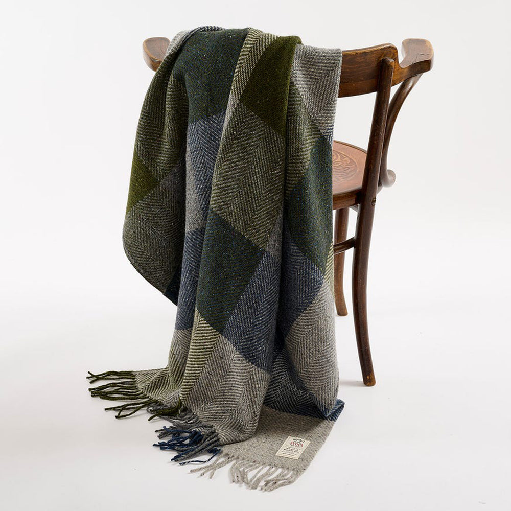Plaid blanket draped over a wooden chair on a white background