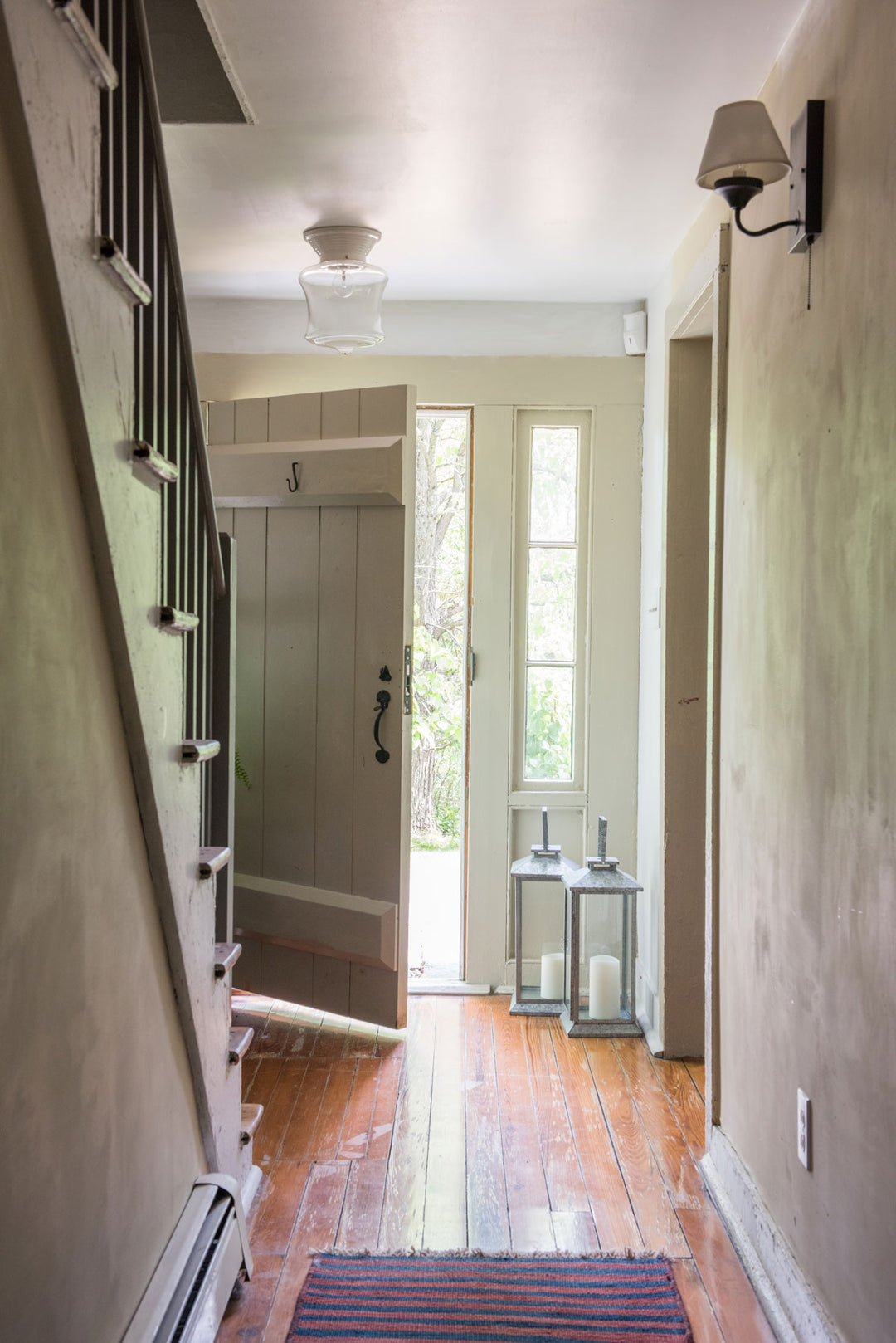 Hallway in old Colonial-style house with neutral colors, open door, and hardwood floors